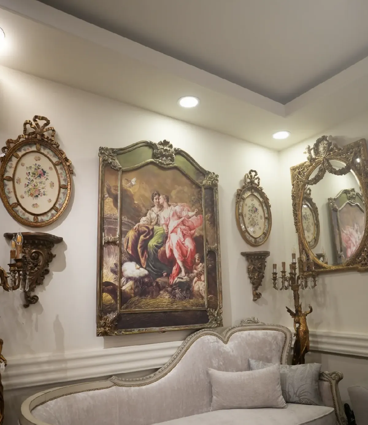 الركن نفسه بعد التجديد: جدار أبيض ولوحة زيتية بإطار مذهّب وكنبة كلاسيكية فاتحة
