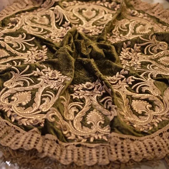 مخمل زيتوني عليه تطريز ذهبي بارز عن قرب
